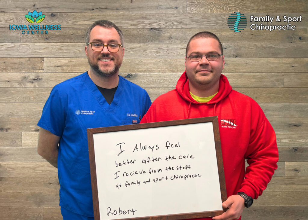 Chiropractor and patient hold sign that explains how this longevity center near Cedar Rapids helps people find relief from neuropathy through ongoing support