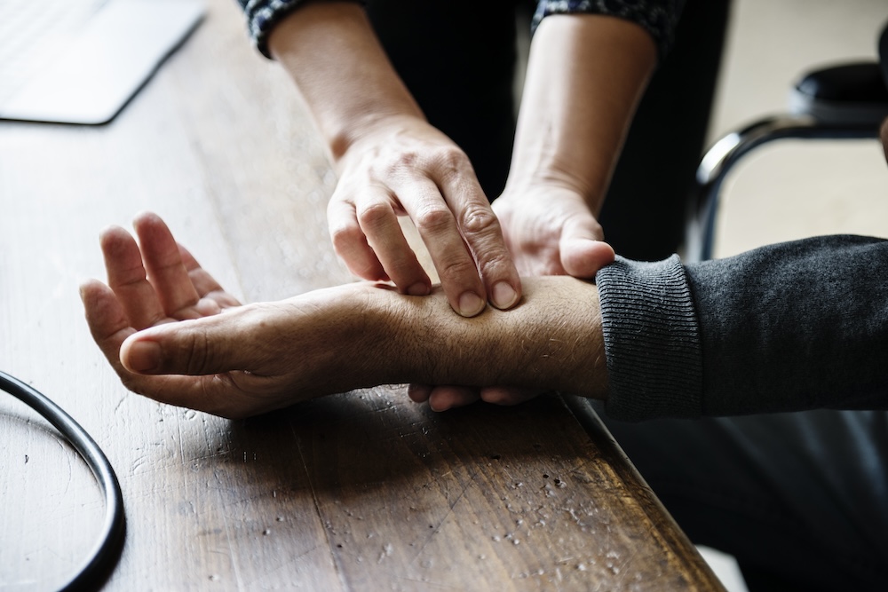 Person holds hands out while medical professional presses down on their wrist to find the source of pain and determine the best neuropathy treatment near Cedar Rapids