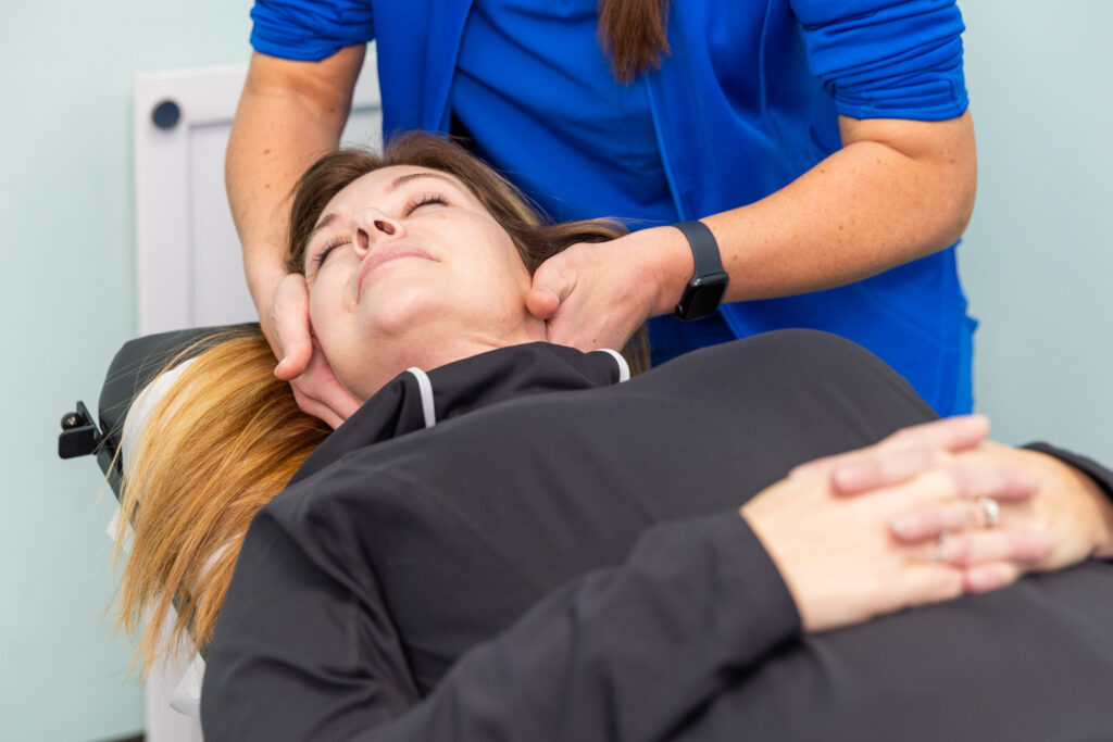 Chiropractor applies pressure to sides of patient's neck as part of a sports massage in North Liberty to improve performance and help accelerate recovery.