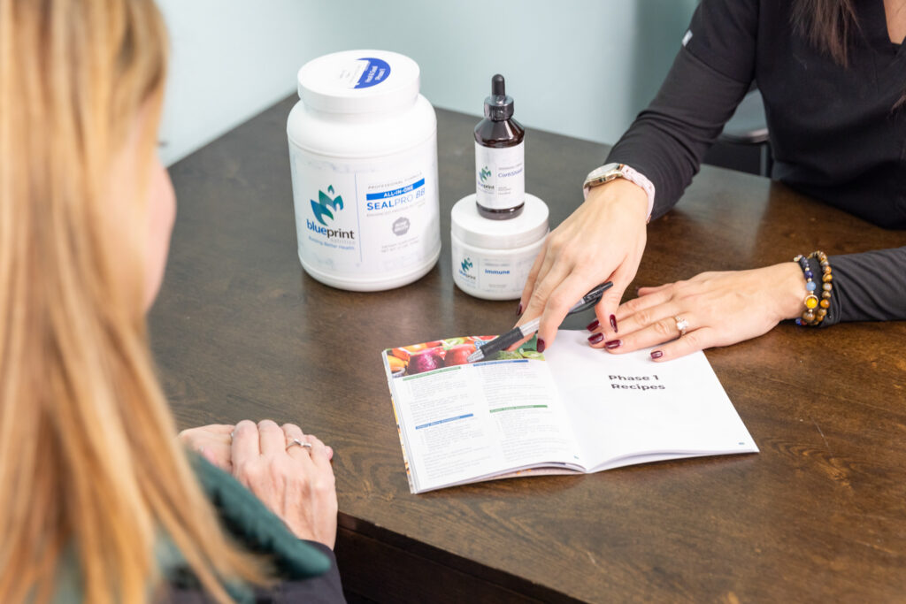 Provider's hands point to a section in informational papers on a desk to pinpoint how medical weight loss near Iowa City can help the patient find joint pain relief.