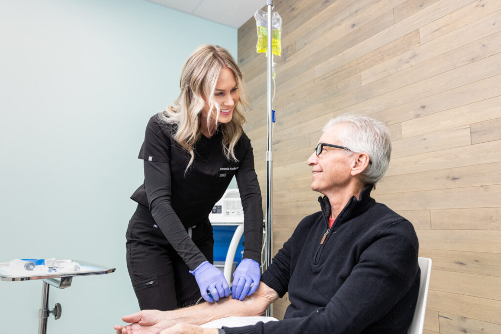 Blonde medical professional wearing purple gloves administers IV therapy into patient so she receives enough nutrients to support her journey with functional medicine in North Liberty.