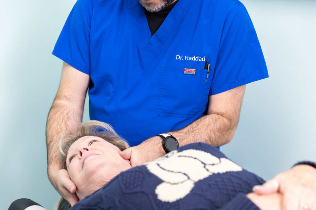 Woman laying on back while chiropractor places hands on both sides of her face and near her neck as part of a comprehensive treatment for physical therapy near Iowa City.