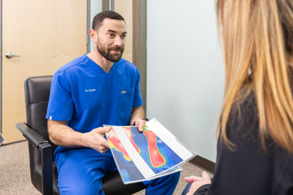 A chiropractor near Iowa City and his patient discussing imaging results from neurofeedback to discuss the best neuropathy treatment for her.