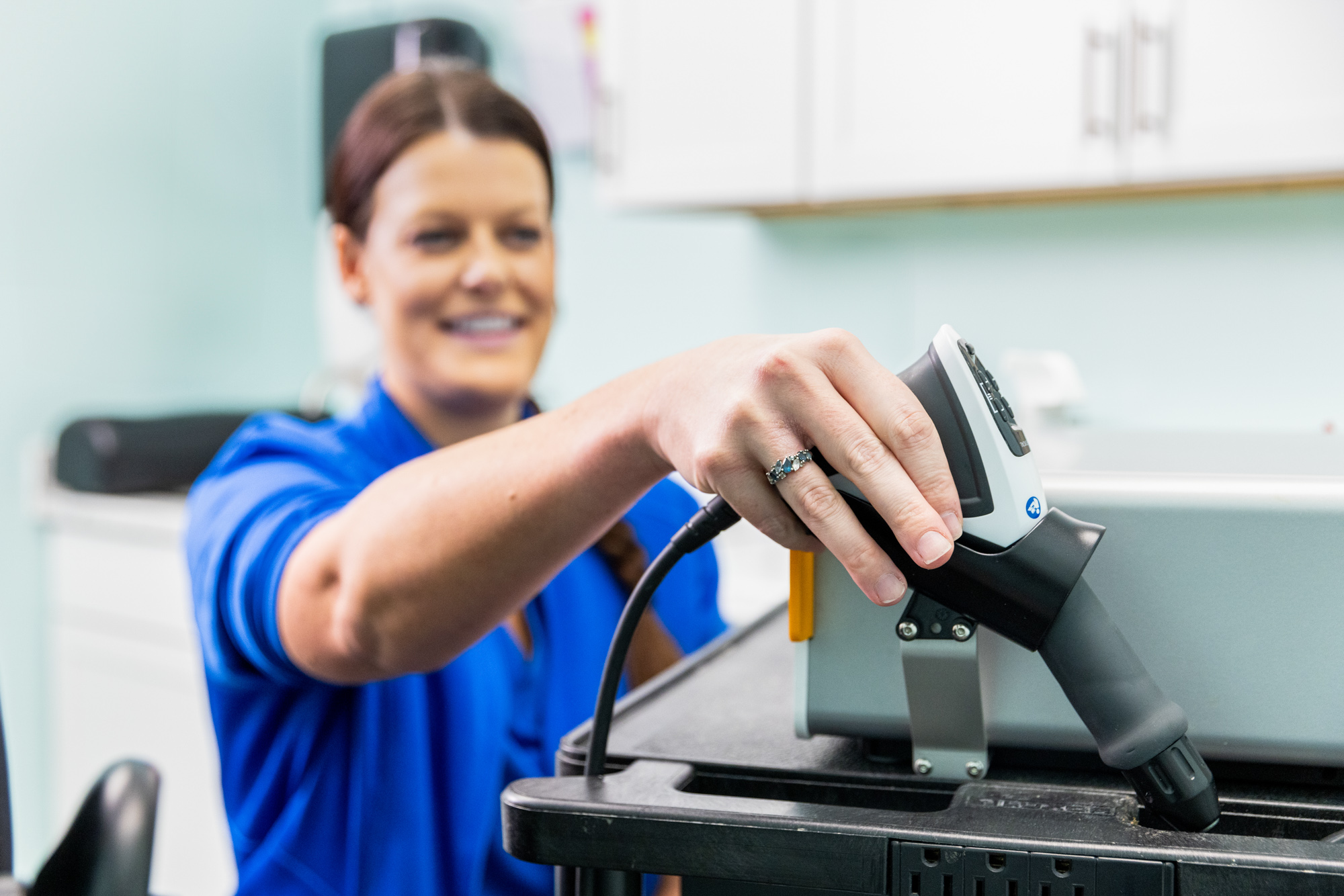Provider grabbing a shockwave device with one hand. She's using regenerative medicine in North Liberty to help her patient reduce pain and improve mobility.